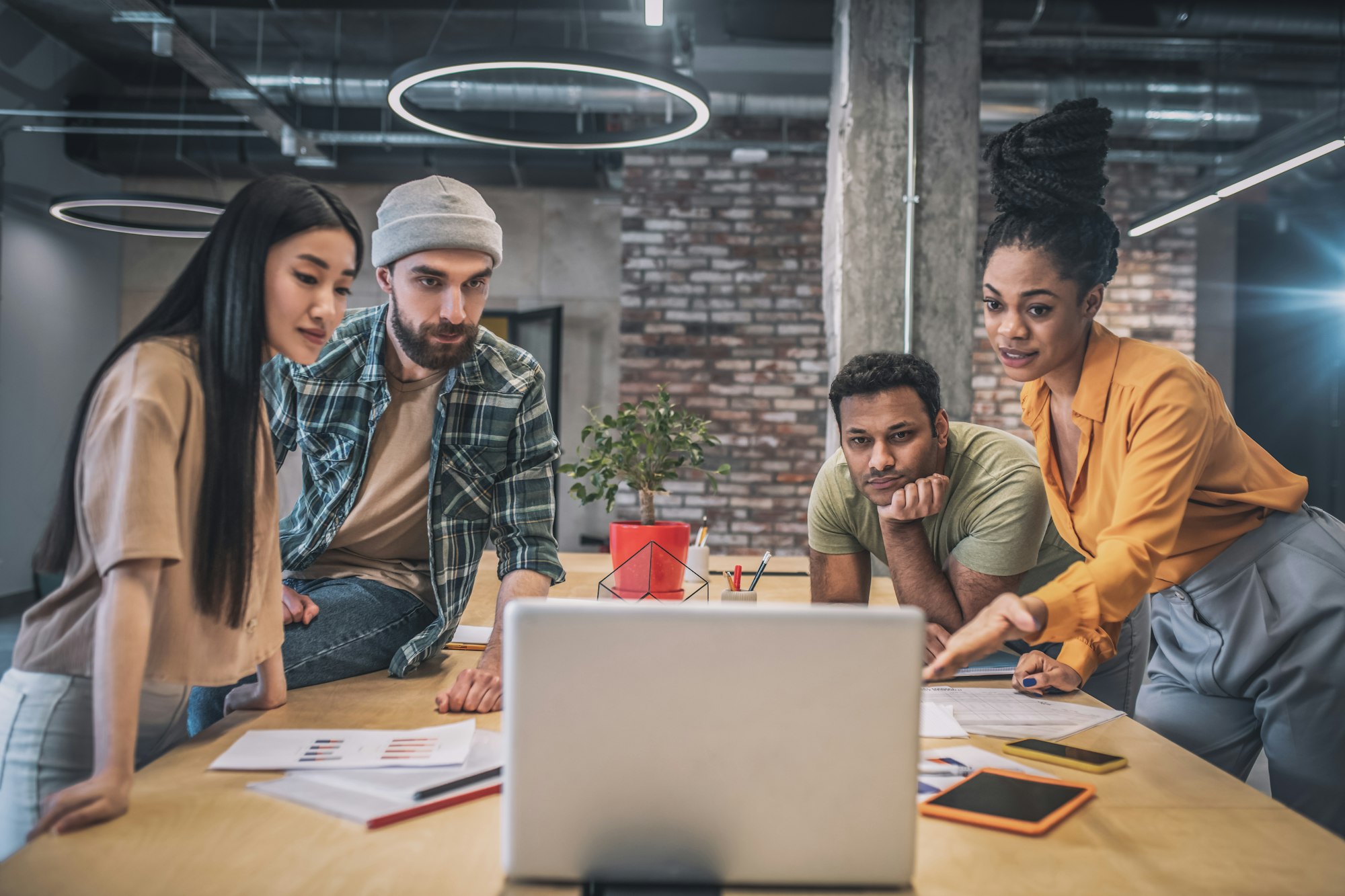 Guys and girls looking attentively at laptop in office